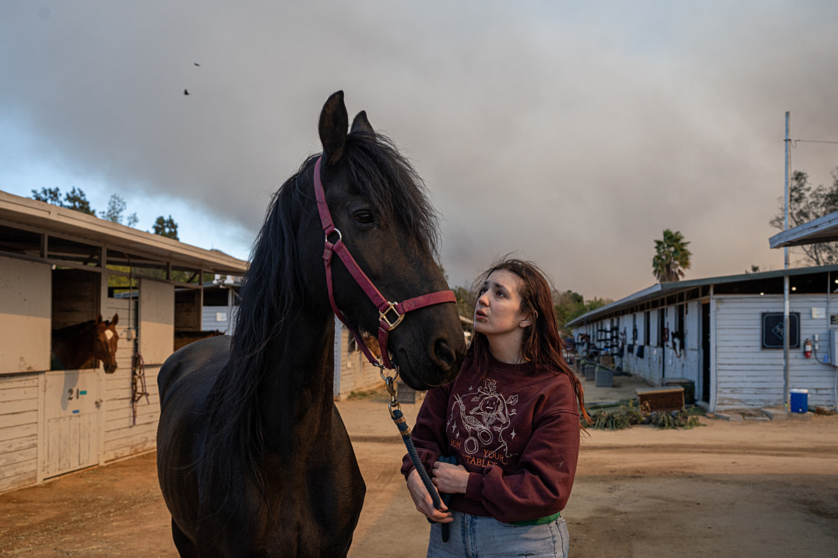 Samantha speaks sweetly to her horse, Bela at the Los Angeles Equestrian Center. Bela was evacuated in the early hours of the morning from the Eaton Dam Stable, which burned down a few hours later in the Eaton Fire near Pasadena. Los Angeles Equestrian Center, Burbank, California, USA, 2025. Thomas Machowicz / Sanctuary Doc / We Animals