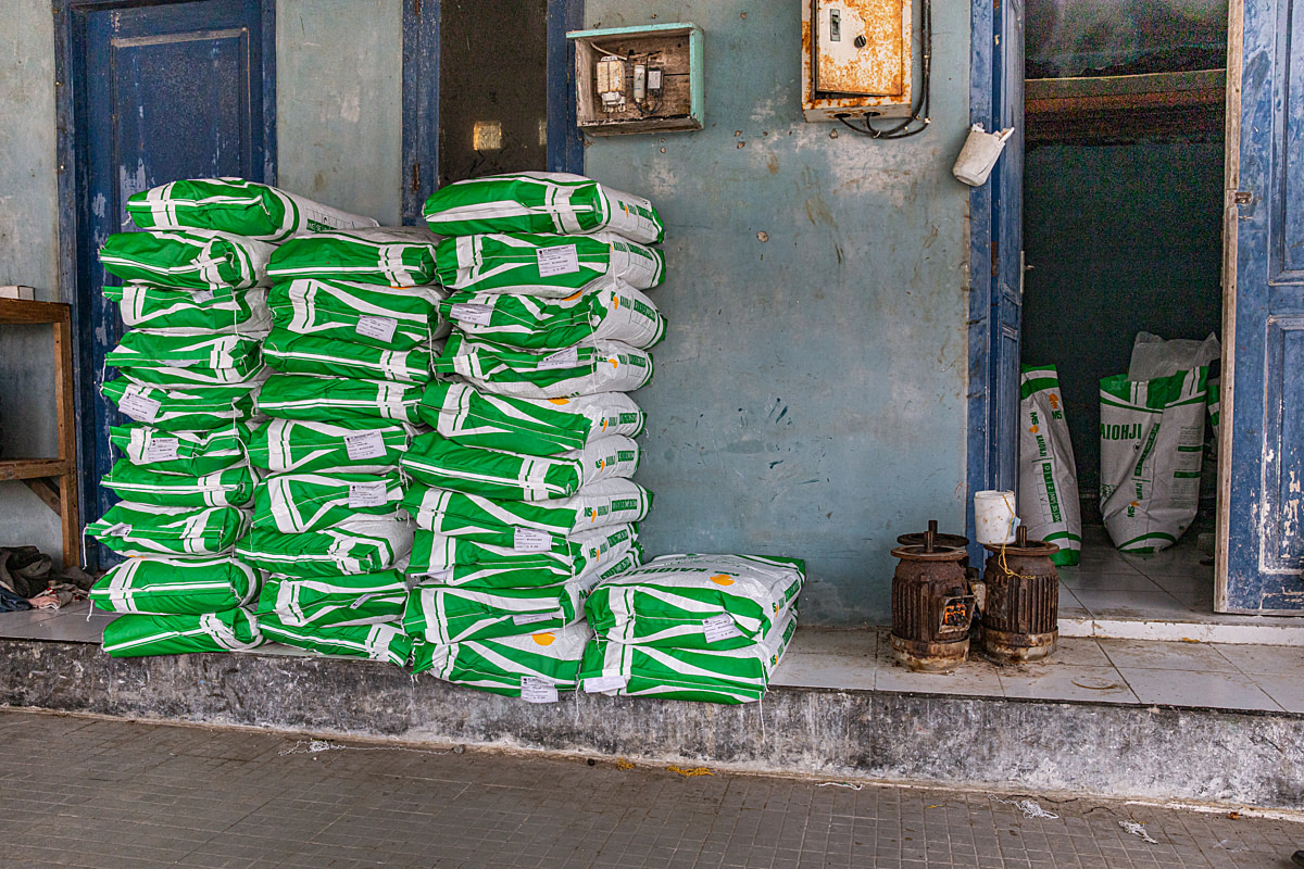 Bags of shrimp feed manufactured by PT Matahari Sakti sit stacked beside a storage room at a shrimp farm. Undisclosed location, Tuban, East Java, Indonesia, 2026. Ulet Ifansasti / Animal Welfare Observatory / We Animals