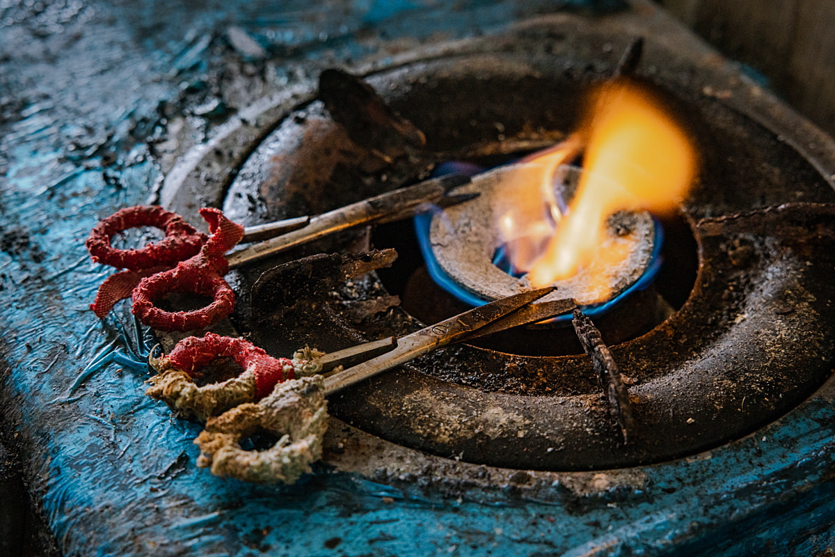 Scissors are heated over an open flame in preparation for the ablation process of female broodstock shrimp at a shrimp hatchery. Undisclosed location, East Java, Indonesia, 2026. Ulet Ifansasti / Animal Welfare Observatory / We Animals