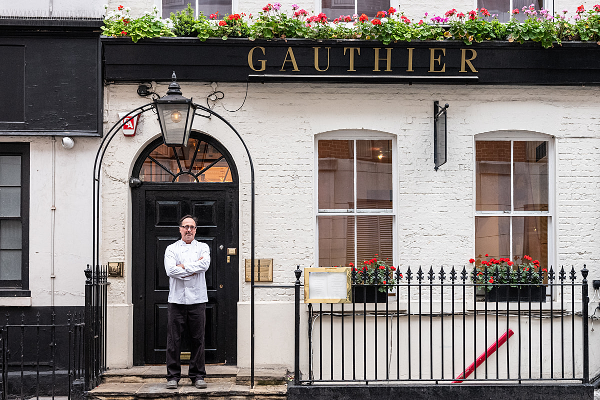 Chef Alexis Gauthier poses for a portrait in front of Gauthier Soho, his restaurant located in a London Soho townhouse. Gauthier Soho, London, United Kingdom, 2024. Nathalie Merle / We Animals