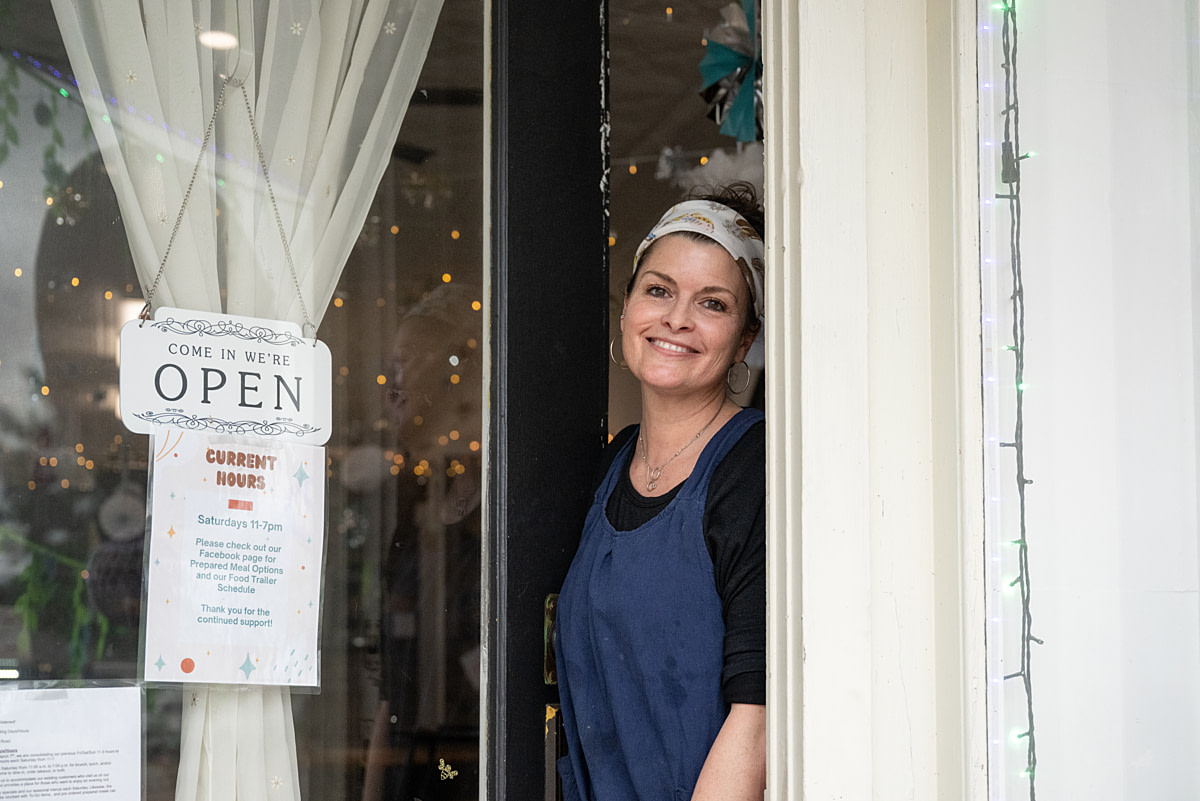 A portrait of The Tasty Plate Cafe's founder Dustie Condon at the entrance to her plant-based restaurant. Morgantown, Indiana, USA, 2025. Jo-Anne McArthur / We Animals