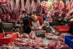 Vendor chops slabs of meat and hangs them for sale at a wet market in Taipei. Taiwan, 2019.