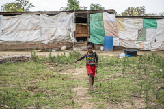 A child plays outside a barn that holds 1,500 chickens who are being raised for meat on a small-scale farm.