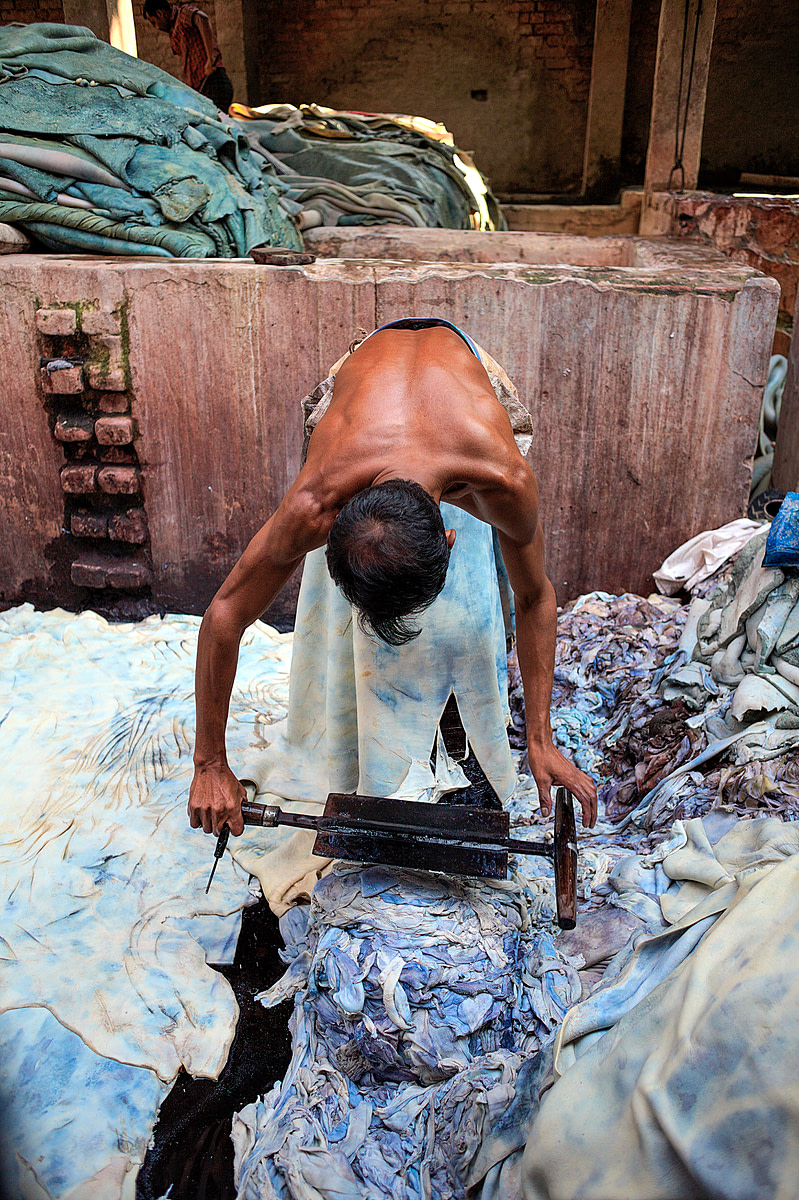 In Hazaribagh, a part of western Dhaka reknowned for its tanneries, a worker bends over a cow hide. Using a specially formed knive, he removes the chemically dissolved layer of fat from the skin. Bangladesh, 2015. Christian Faesecke / We Animals