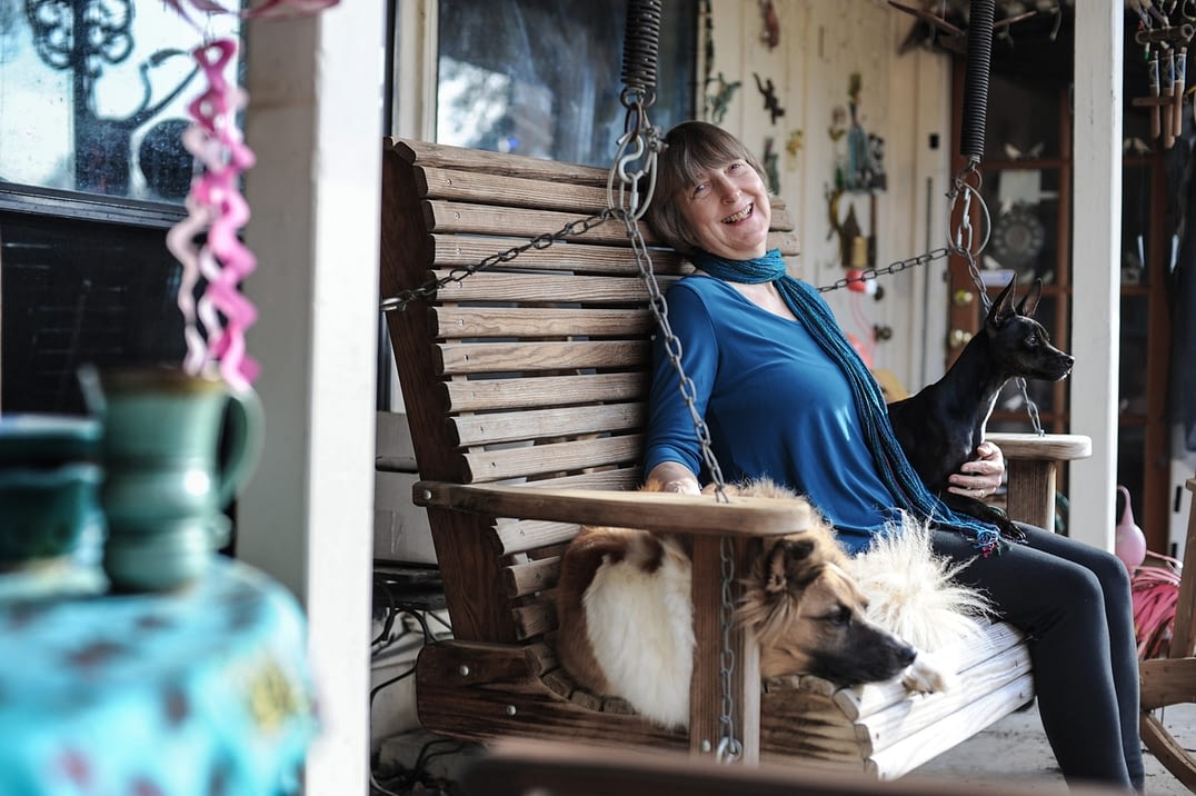 Carol on her front porch with rescue dogs, Holly and Inky. USA, 2015.