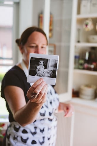Hannah Murray holds up a photo of her mother as a child, eating from the same plates that she now serves food on. Tradition and family are important to this animal justice advocate. Photo by Victoria de Martigny / #unboundproject / We Animals Media