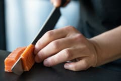 Chef Jun Sog slices a piece of cultivated salmon in Wildtype's test kitchen.