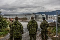 Four members of the Canadian military assess how to transfer more than 10,000 chickens from one farm to another. With no hip waders, these floods posed a great access problem.
