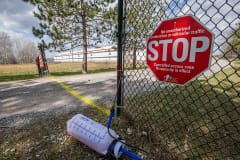 A biosecurity sign announces that no pedestrians or vehicles should enter a large chicken or turkey farm while the highly pathogenic H5N1 avian flu is in the area. Canada, 2022. Jo-Anne McArthur / We Animals Media