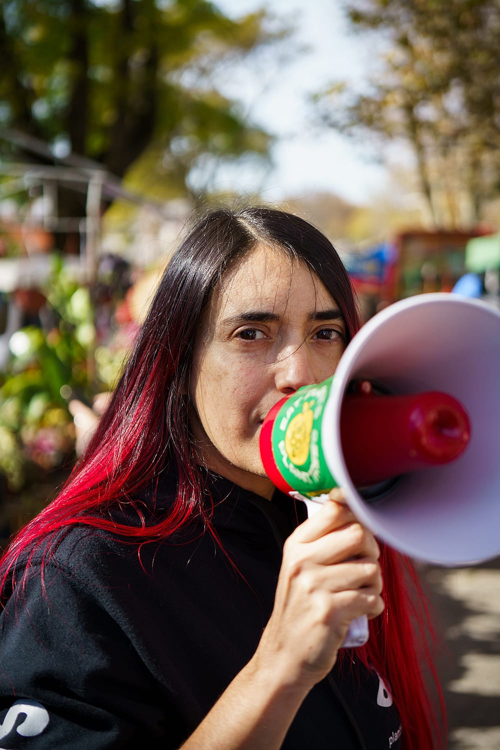 Animal liberation activist Azul Cardozo speaks through a megaphone at a local fair in Montevideo, Uruguay. Azul shares information with local people at the fair as part of the "Plant Based Treaty" campaign, encouraging them to sign the treaty and enjoy a piece of vegan cake. Photo credit: Martina Victoria Zamudio / We Animals Media