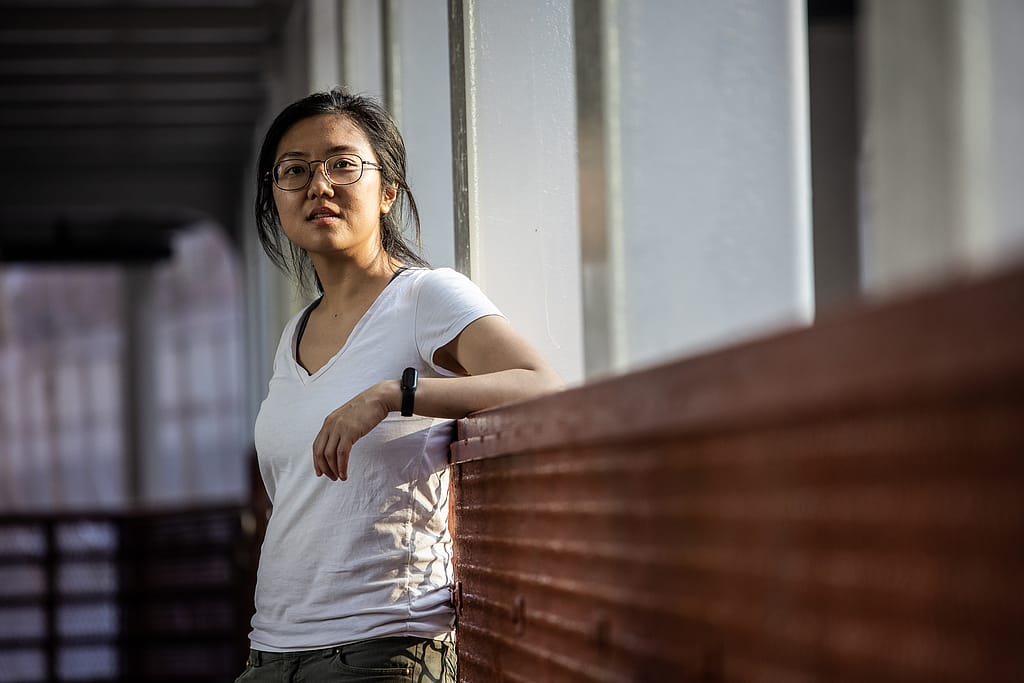 Jah Ying Chung, a food researcher and animal advocate in China, poses for a photo on an urban pedestrian bridge. Jah Ying is the co-founder of The Good Growth Co., which researches Chinese consumers' attitudes toward food and works in the plant-based/alternative protein and animal welfare spaces. Hong Kong, China, 2022. #unboundproject / We Animals Media