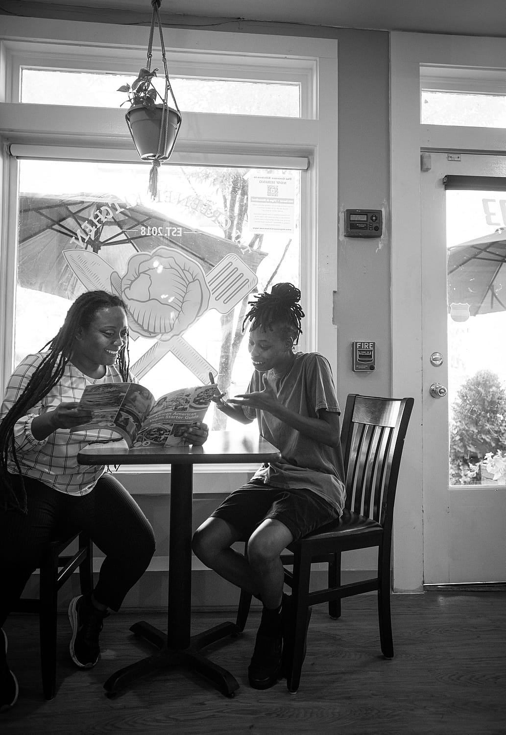 Vegan advocate, humanitarian, and entrepreneur Brenda Sanders looks at the veg guide with a friend at her restaurant in Baltimore, The Greener Kitchen. Photo by: Jo-Anne McArthur / #UnboundProject / We Animals Media.