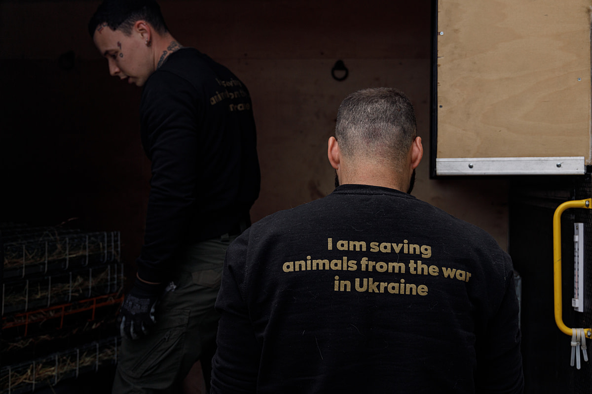 UAnimals rescuer Danya (L) stands inside an evacuation vehicle car near fellow UAnimals rescuer Vlad (R) while they prepare the vehicle for a trip to an evacuation location. Ukraine, 2024. Anzhelika Kozachenko / UAnimals / We Animals Media