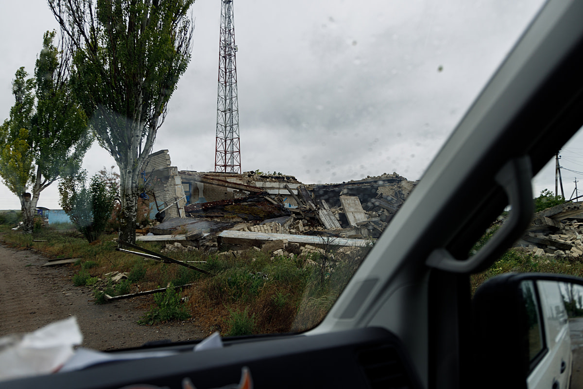 A view through the windshield of an animal evacuation van of a destroyed building on the outskirts of a village. The building was destroyed by Russian shelling during the Russia-Ukraine war. Ukraine, 2024. Anzhelika Kozachenko / UAnimals / We Animals Media