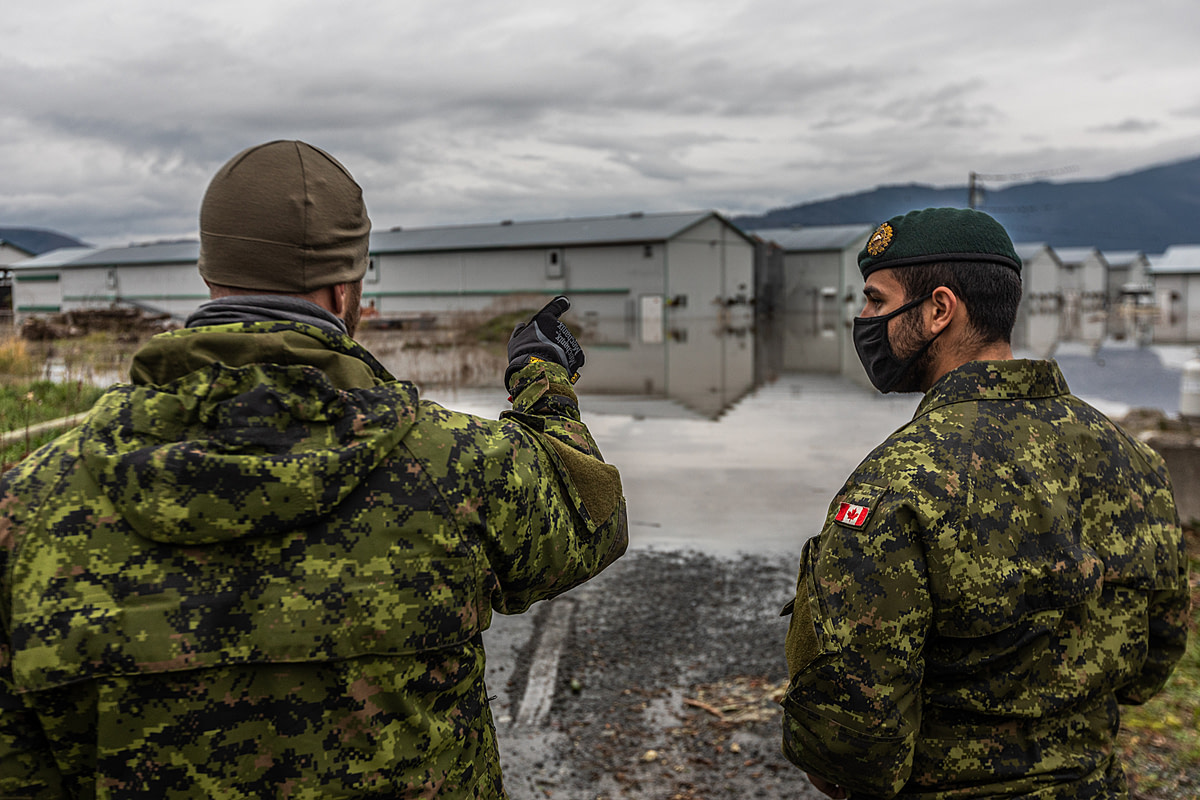 Two members of the Canadian military discuss plans for how to move more than 10,000 chickens from one barn to another during a devastating flood in Abbotsford, BC. Canada, 2021. Nick Schafer / We Animals Media