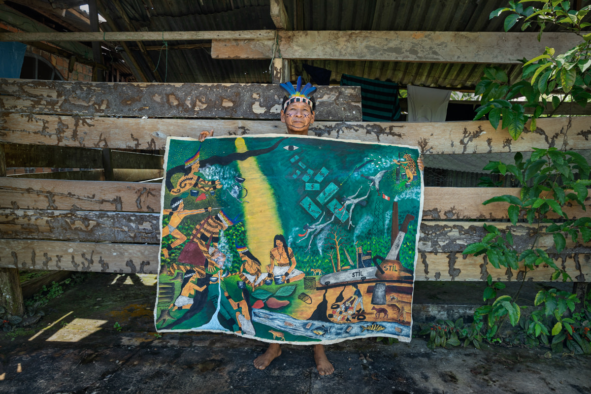 The painter Santiago Yahuarcani shows his work “The Amazon Jungle is Dying”. Caballococha, Department of Amazonas, Peru, 2019. Ana Palacios