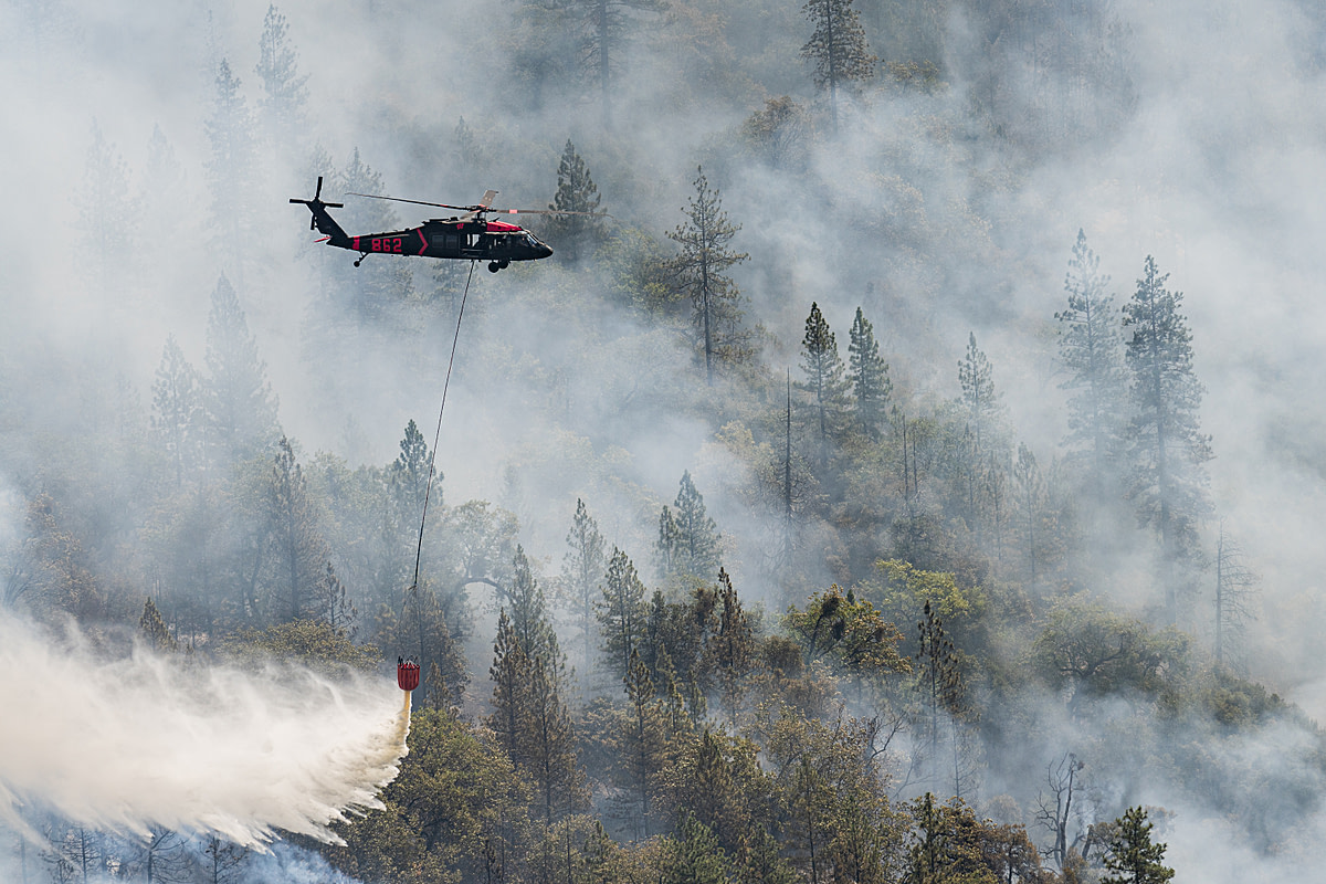 Helicopters work continually throughout the day dropping water on a hot zone that erupted near the fire decimated town of Grizzly Flats. California, USA, 2021. Nikki Ritcher / We Animals Media