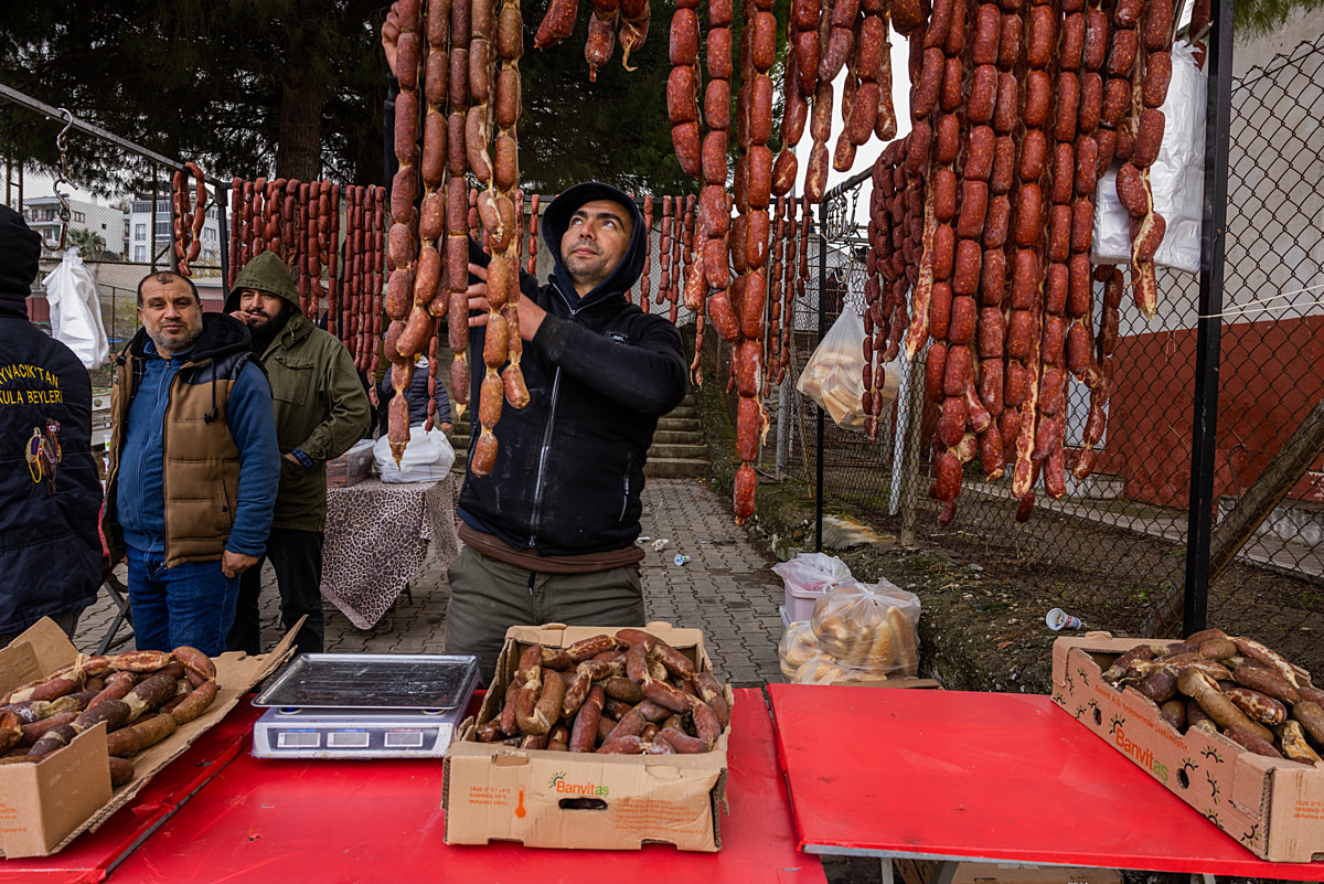 A vendor arranges long links of camel meat sausages in his stall at a camel wrestling festival. Canakkale Province, Turkiye, 2023. Jane Mar / We Animals Media