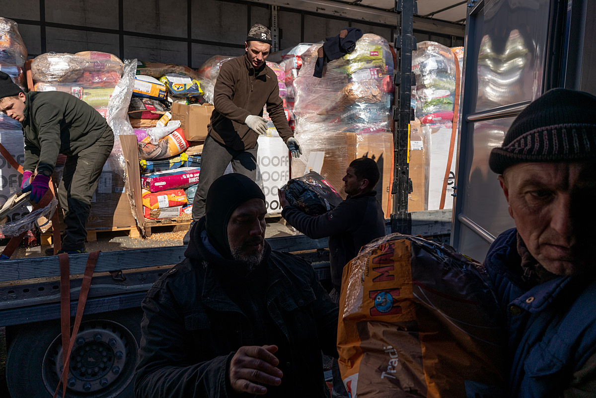 Fundacja Centaurus workers unload a truck of animal food and supplies shipped from Holland into a container at the Fundacja Centaurus aid camp. Poland, 2022. Thomas Machowicz / We Animals Media