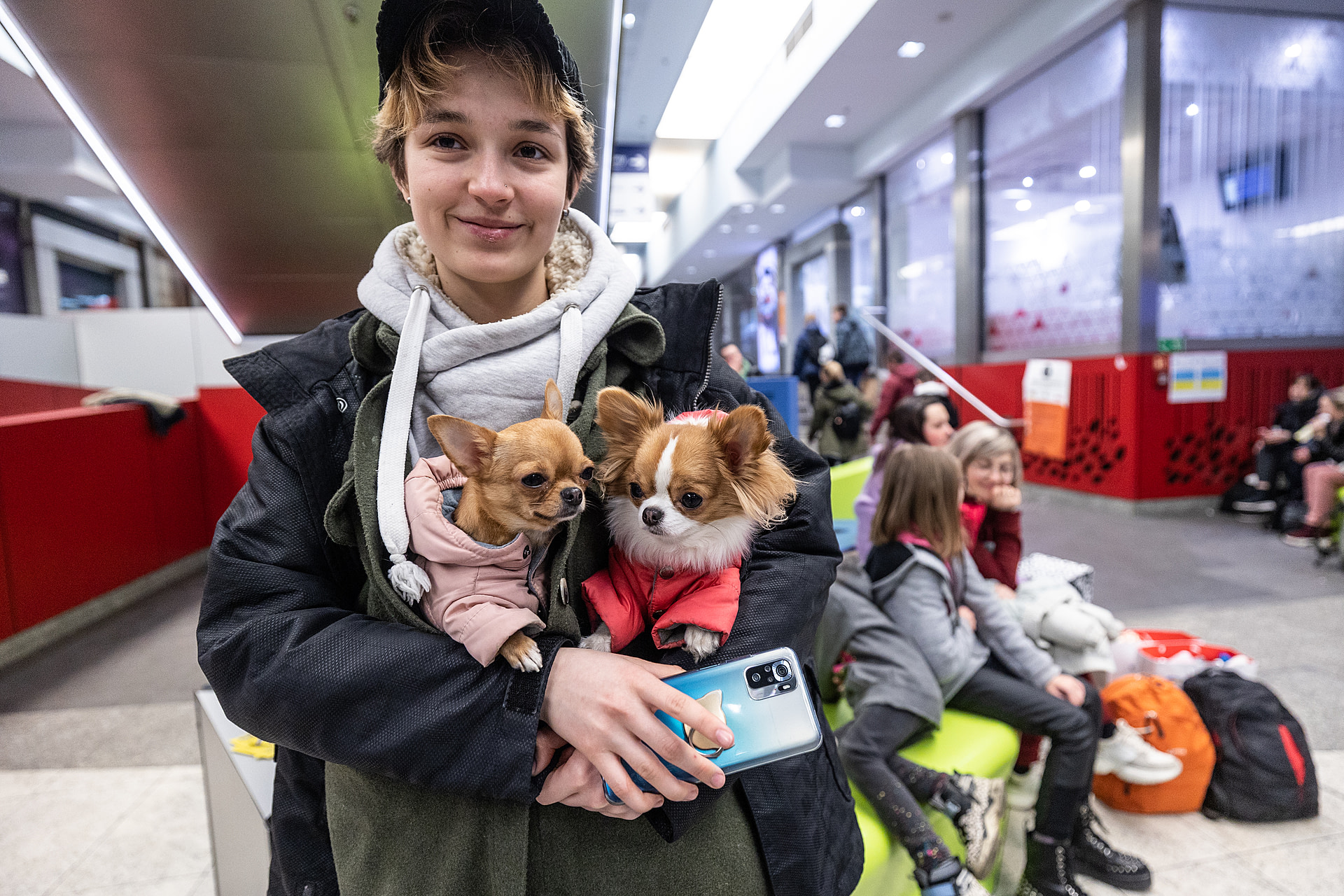 Tatiana, a young Ukrainian refugee, carries two small dogs though the train station in Kraków. They escaped from Kharkiv and are heading to Spain.