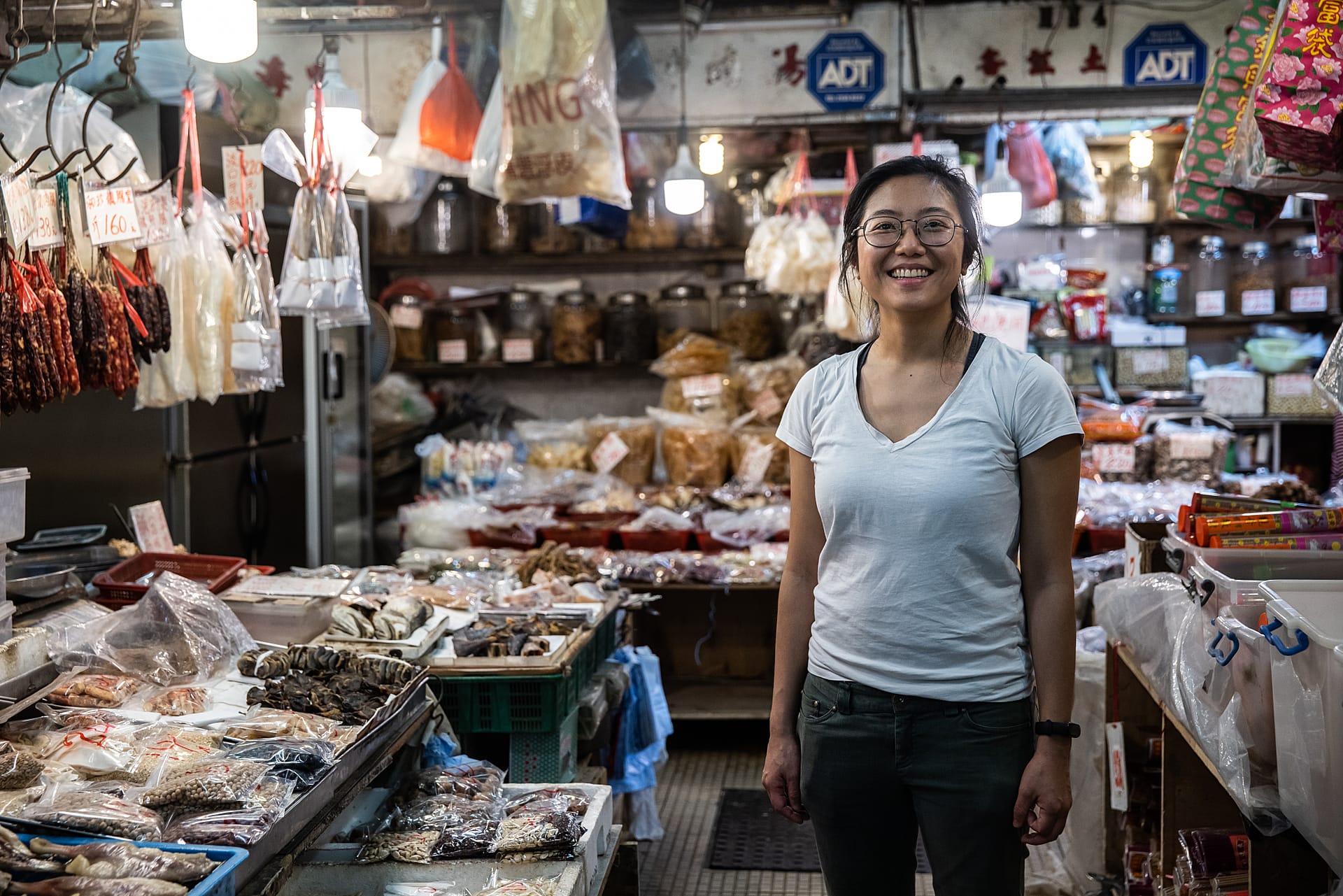Jah Ying Chung, a food researcher and animal advocate in China, stands in a packaged food aisle of a store that is also a wet market. Jah Ying is the co-founder of The Good Growth Co., which researches Chinese consumers' attitudes toward food and works in the plant-based/alternative protein and animal welfare spaces. Hong Kong, China, 2022. #unboundproject / We Animals Media