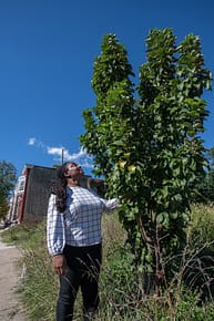 Brenda Sanders looks up at one of the remaining apple trees that was planted as part of her initiative to create community gardening spaces in Baltimore. Photo by: Jo-Anne McArthur / #UnboundProject / We Animals Media.