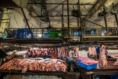 Slabs of pig meat are stacked in the open under small ceiling fans at a wet market in Taipei. Taiwan, 2019.