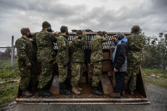 Six members of the Canadian military and one chicken catcher assemble in the bucket of a front loader. They are about to be driven through the floodwaters to access a chicken barn and relocate over 10,000 chickens.