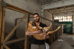 An American volunteer holds a Ukrainian shelter dog by the kennels at Domivka Vryatovanykh Tvaryn, an animal shelter and temporary holding facility for animals displaced by war in Lviv. Ukraine, 2022.  Molly Condit / We Animals Media