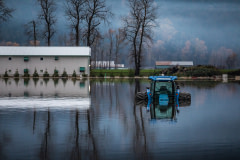 A tractor and chicken barn sit partially submerged in floodwaters in Abbotsford, BC.