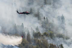 Helicopters work continually throughout the day dropping water on a hot zone that erupted near the fire decimated town of Grizzly Flats.