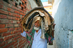 An elderly worker carries a dozen cow hides on his head through the narrow streets of Lalbagh, in the centre of Dhaka. Bangladesh, 2015. Christian Faesecke / We Animals Media