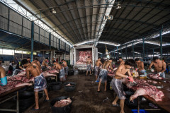 Butchering pig carcasses at an outdoor market.