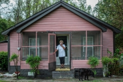Activist Elsie Herring, stands on the porch of her family home, holding a handkerchief over her mouth to filter out manure being sprayed on the field next door. North Carolina, USA.