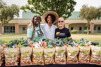 Gwenna Hunter, Avaion Ruth, and Kim King with Vegan Outreach stand in front of roughly 100 bags of fresh local produce given to local communities impacted by the COVID-19 crisis in Los Angeles. Photo by Nikki Ritcher / #unboundproject / We Animals Media.