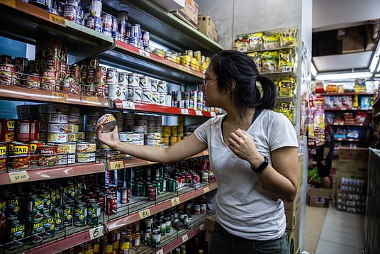 Jah Ying Chung, a food researcher and animal advocate in China, browses tinned foods on the shelves of a grocery store. Jah Ying is the co-founder of The Good Growth Co., which researches Chinese consumers' attitudes toward food and works in the plant-based/alternative protein and animal welfare spaces. Hong Kong, China, 2022. #unboundproject / We Animals Media
