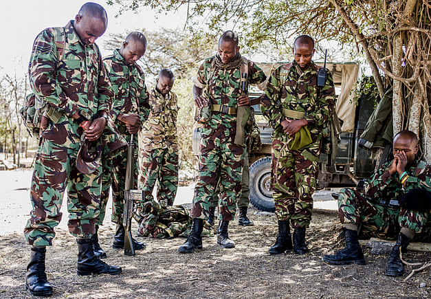 NPR (National Police Reservists) have a moment of prayer before they go out on an overnight patrol of Ol Pejeta Conservancy in Central Kenya. The armed men patrol the 360 km2 (140 sq mi) not-for-profit wildlife conservancy around the clock and protect the rhinos and other animals from deadly poachers. Kenya, 2019. Justin Mott / Kindred Guardians Project / We Animals Media