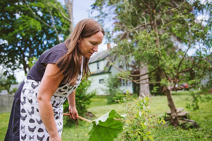 Hannah Murray examines a blueberry bush in her garden. Since her day job as a grant writer keeps her inside at her desk, she makes it a point to spend time outdoors in her garden where she can grow some of her favorite herbs, fruits and vegetables. Photo by Victoria de Martigny / #unboundproject / We Animals Media