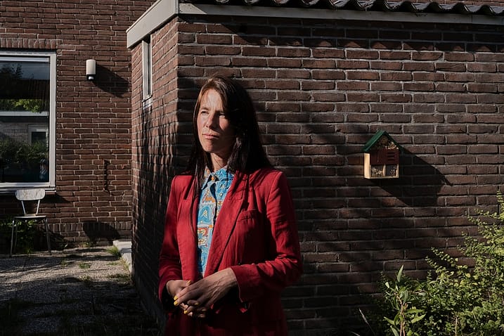 Eva Meijer stands in the backyard of her home. In her work, the Dutch philosopher, writer, and artist focuses on the languages and communication of animals, as well as on the relationship between humans and animals, and the politics around the subject. North Holland, Netherlands. 2022. Sabina Diethelm / #unboundproject / We Animals Media