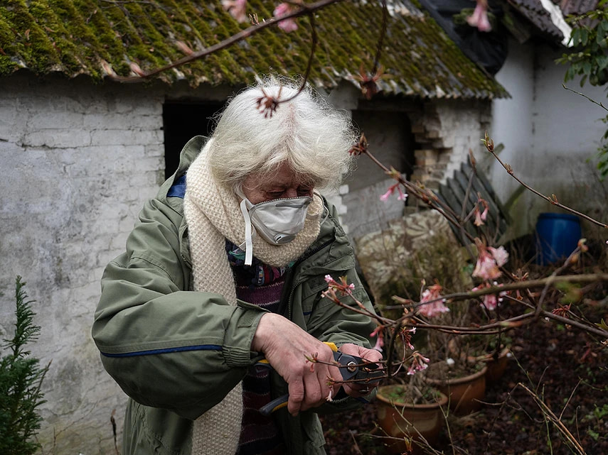 Woman who lives close to a factory farm is gardening outdoors wearing a face mask daily because of smell and pollution. Denmark, 2019. Selene Magnolia / Wildlight / Greenpeace